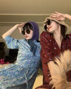 two women sitting next to each other in front of a mirror wearing hats and sunglasses