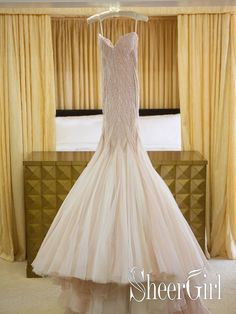 a wedding dress hanging on a rack in front of a window with curtains and drapes