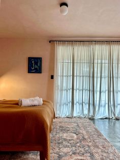 a bed sitting in a bedroom next to a window with curtains on the windowsill