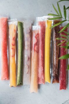 five different types of food wrapped in plastic bags on a table next to a plant