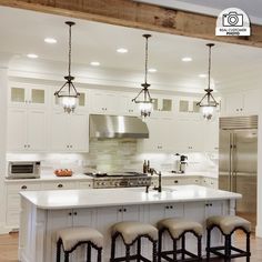 a kitchen with an island and four stools in front of the stove top oven