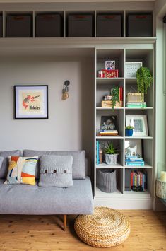 a grey couch sitting in front of a book shelf