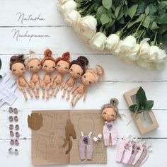 there are many dolls on the table next to flowers and other items for making doll clothes