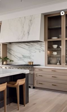 a large kitchen with marble counter tops and wooden stools in front of an oven