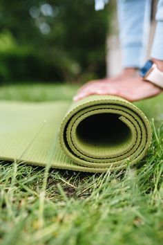 a rolled up yoga mat laying on the ground with someone holding it in their hand