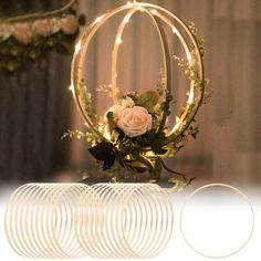 an arrangement of flowers and rings on a table with lights in the shape of circles