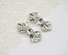 two pairs of crystal earrings on a white lace background