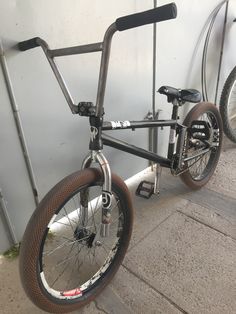 a bicycle parked next to a wall with two bicycles on it's back wheels