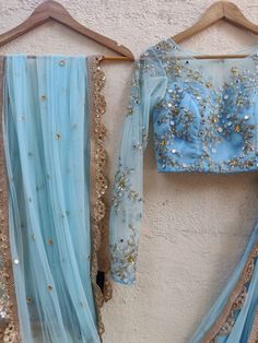 This fresh powder blue raw silk lehenga has thread and sequin butti embroidery all over.  It is paired with a mirror, sequins, beads and thread embroidered tulle blouse. The outfit is completed with an embroidered net dupatta. Butti Embroidery, Tulle Blouse, Raw Silk Lehenga, Mirror Work Blouse, Blue Umbrella, Embroidered Tulle, Gold Border, Silk Lehenga, Net Dupatta