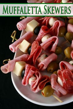 there are many different types of skewers on the plate with olives and cheese