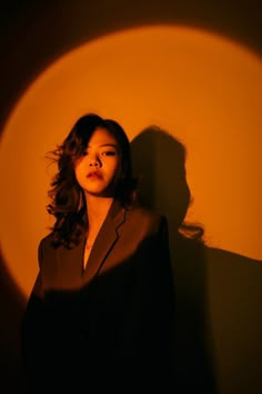 a woman standing in front of a wall with her shadow on the wall behind her