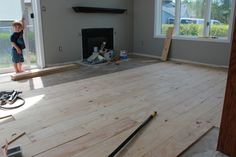 a young boy standing on top of a wooden floor in a living room under construction