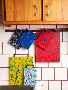 four pieces of colorful paper hanging on a kitchen wall