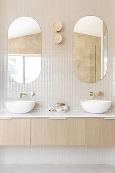 two white sinks sitting under round mirrors in a bathroom next to a wall mounted faucet