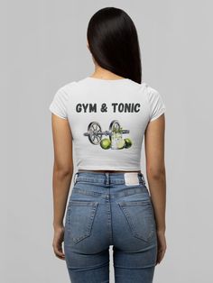 "The T-shirt for gym girls with the slogan \"Gym and Tonic\" combines a playful twist on the classic \"gin and tonic\" with a fitness-oriented theme. It's a fun and witty way to express the idea that hitting the gym is their refreshing tonic and an essential part of their routine, just like a good drink. This shirt is perfect for those who love a dose of humor in their workout attire. This crop top has both comfort and style in spades. Made 100% with silky soft polyester that is both lightweight and breathable." Fitted Sports T-shirt With Graphic Print, Stretch Sports T-shirt With Text Print, Sports Cotton Crop Top T-shirt, Trendy Fitted Cropped T-shirt For Workout, Fitted T-shirt For Gym And Summer, Sports Letter Print Crop Top T-shirt, Sporty Graphic Print Crop Top For Workout, Basic Fitted Workout T-shirt, Sporty Crop Top T-shirt For Workout