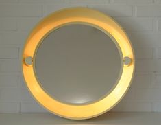 a yellow lighted mirror sitting on top of a white table next to a brick wall