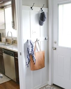 an open door with a purse hanging on the wall next to a sink and dishwasher