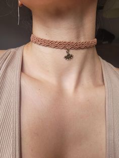 a woman wearing a brown choker with a cross pendant on it's neck