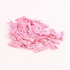 a pile of pink plastic clothes pegs sitting on top of a white surface