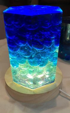 a blue and green vase sitting on top of a wooden stand next to a glass container