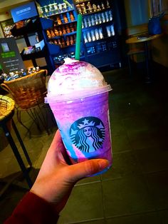 a hand holding up a purple and blue drink