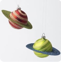 two christmas ornaments hanging from strings in the shape of saturn and uranos with glitter on them