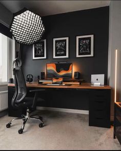 a home office with black walls and pictures on the wall, along with a computer desk