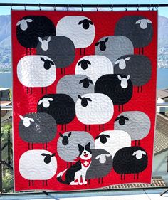 a red and black quilt with sheep on it