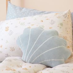 a close up of pillows on a bed with sea shells and stars in the background