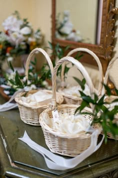 two wicker baskets sitting on top of a table with napkins and flowers in them