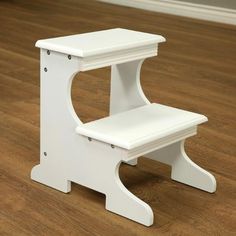 a white step stool sitting on top of a hard wood floor