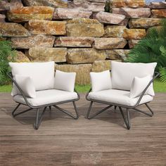 two chairs sitting next to each other on a wooden floor in front of a stone wall