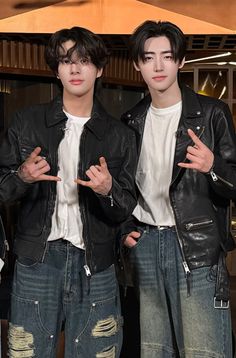 two young men standing next to each other with their hands in the air while wearing black leather jackets