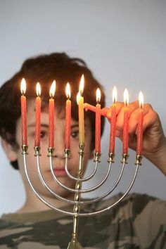 a young boy holding a lit menorah with seven candles in front of his face