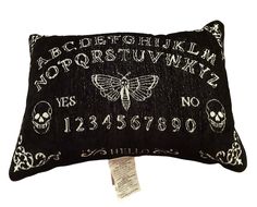 a black pillow with white embroidered letters and skulls on the front, along with a butterfly