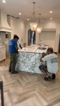 two men working on a marble counter in a kitchen