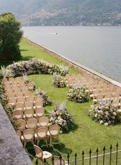 an outdoor ceremony setup with chairs and flowers on the lawn by the water's edge