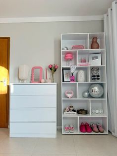 a white book shelf filled with lots of pink and white items next to a door