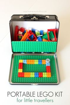 an open suitcase filled with legos on top of a white table next to a phone