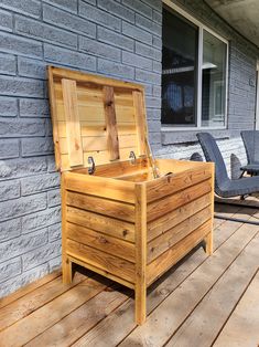 a wooden chest sitting on top of a wooden deck next to a chair and table