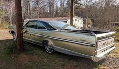 an old car is parked in the grass near a pole and some wood post posts