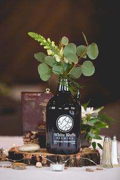 a bottle with some flowers in it sitting on a table