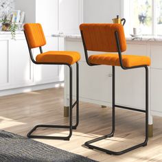 two orange chairs sitting next to each other on a wooden floor in front of a window