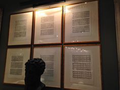 four framed sheet music manuscripts on display behind a busturine's head