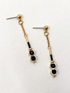 These earrings are dainty and minimalistic but detailed! Thick, straight cut, golden brass rings encircle each semi precious stone of matte black onyx, complimentary tiny, matte black glass seed beads sit above.  The shiny warm, golden brass contrasts beautifully with the deep black stone.  The simplicity and geometric shapes create a contemporary design.  A solid brass ball stud with stainless steel earring post sits at the top.  Approximate measurements- 5.5 cms long 0.75 cm wide All Set Theory jewellery comes with care instructions and a polishing pad to keep your jewels looking fabulous and shiny! ✨ Minimalist Matte Gold Metal Jewelry, Minimalist Metal Linear Earrings With Adjustable Chain, Tarnish Resistant Black Dangle Jewelry, Black Tarnish Resistant Dangle Jewelry, Minimalist Gold Plated Linear Earrings With Adjustable Chain, Minimalist Tarnish Resistant Black Earrings, Minimalist Black Tarnish Resistant Earrings, Single Black Brass Earring, Black Dainty Metal Jewelry