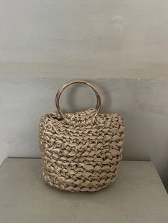 a handbag sitting on top of a table next to a white wall with a wooden handle