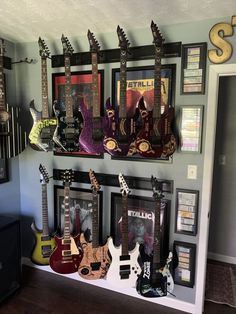 guitars are lined up on the wall in front of pictures and framed photos, along with other musical instruments