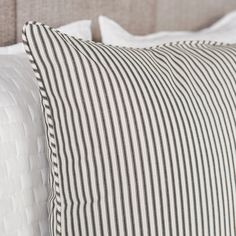 a close up of two pillows on a bed with white and black striped fabric,