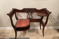 an old wooden desk with a red cushion on it and a chair in the corner