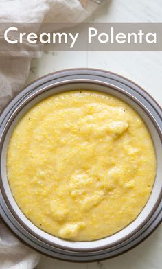 a white bowl filled with yellow sauce on top of a table next to a napkin